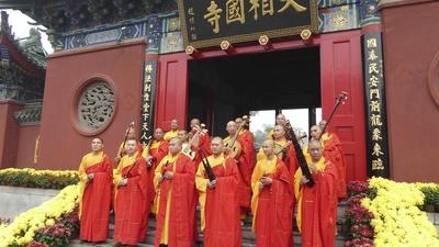 monks standing on steps in front of a temple holding musical instruments