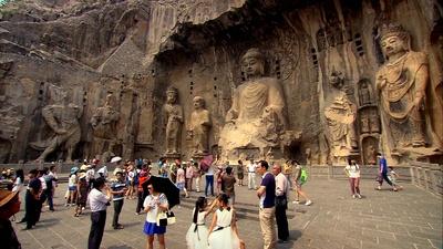Tourists in front of large Buddhist statues carved into a clif