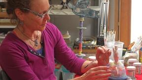 Image of Ceramic artist Susan Garson paints a menorah