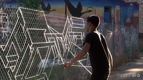 Image of Turning yarn into graphic design on a chain-link fence
