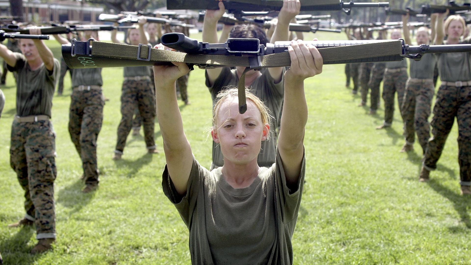 Female military personnel hold up rifles in training exercise