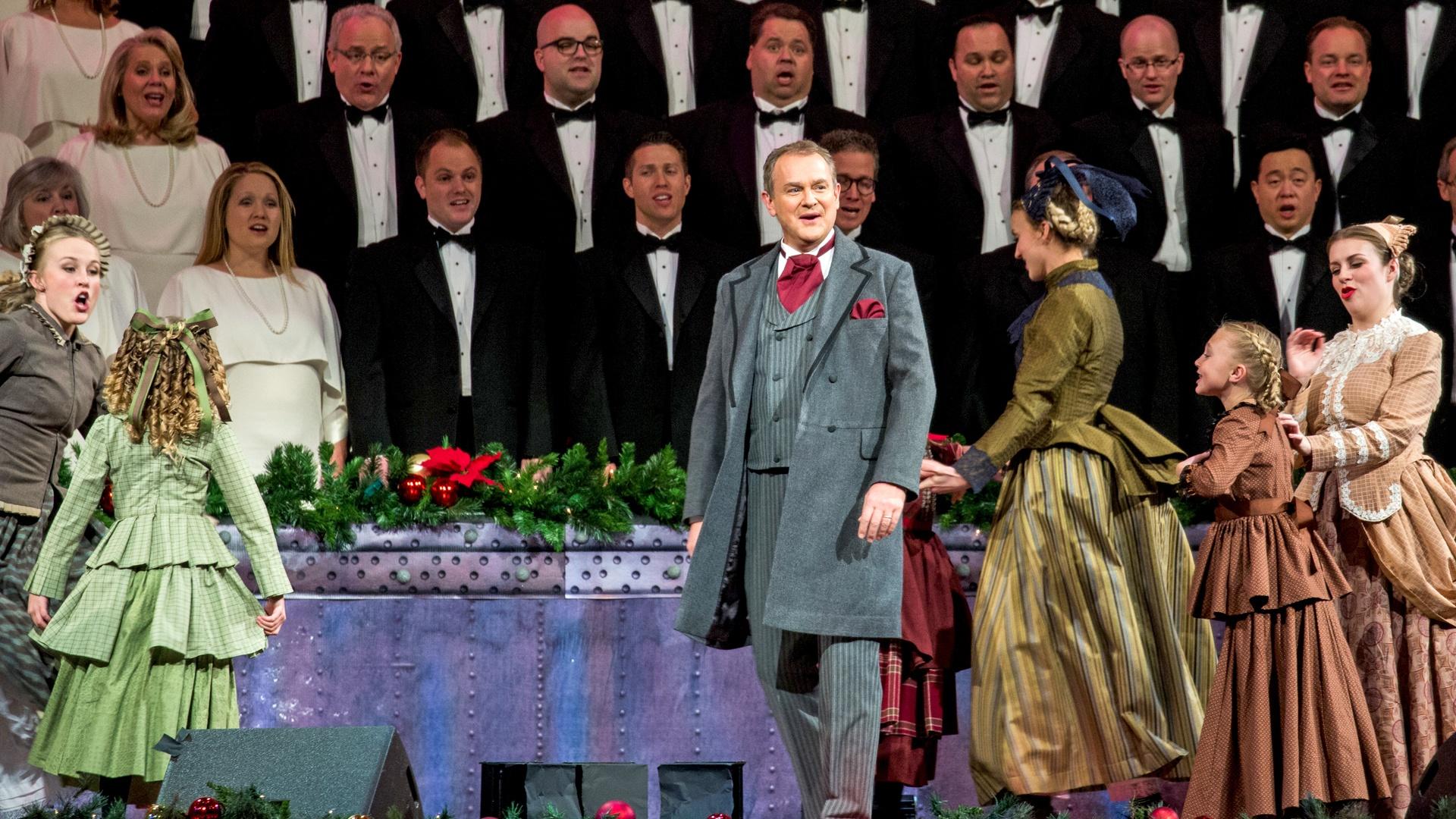 Kristin Chenoweth wears a pale blue dress with fur accents and sings in front of the violinists of The Orchestra at Temple Square.