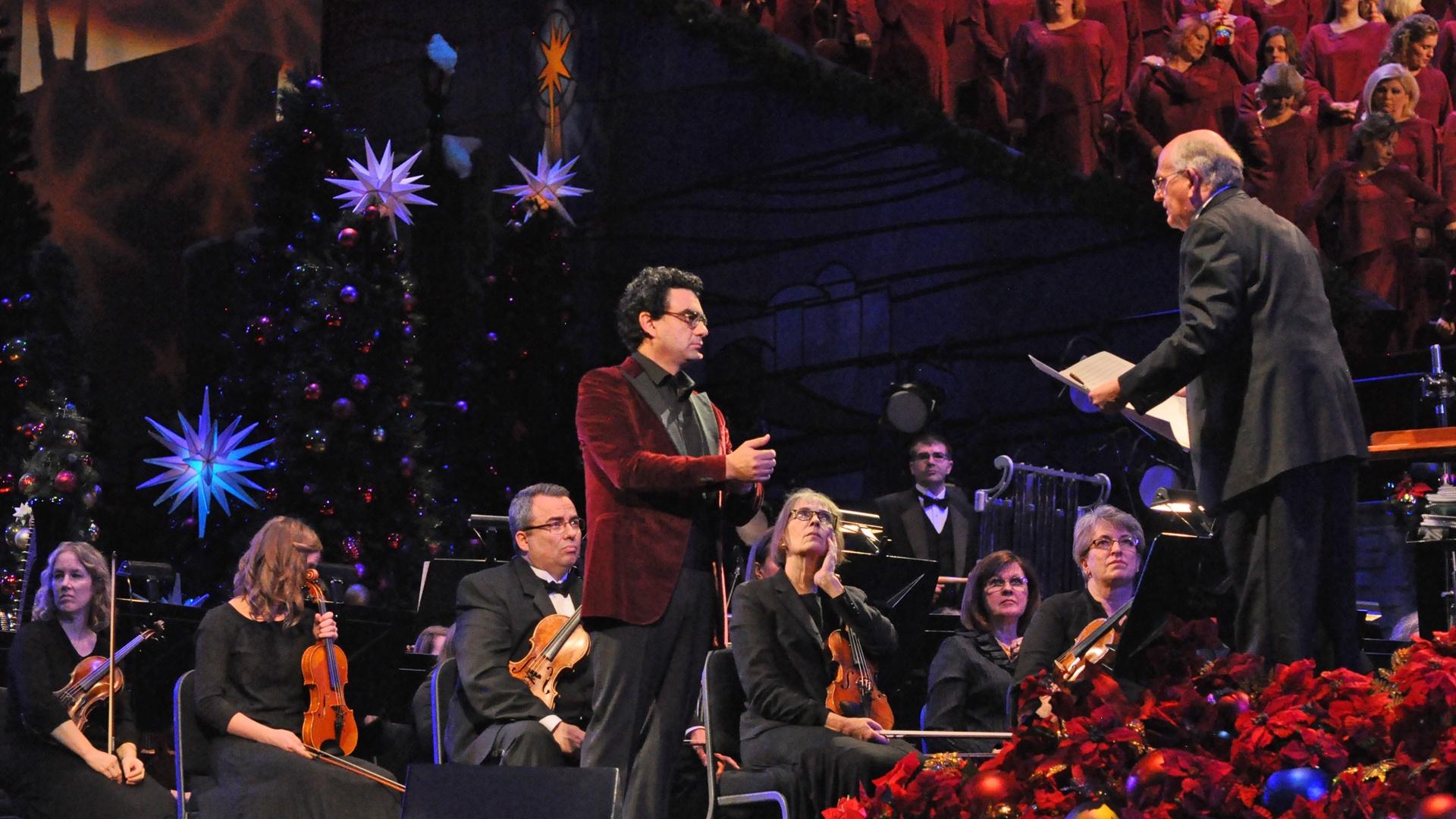 Kristin Chenoweth sings in front of the organist and musicians holding jingle bells.