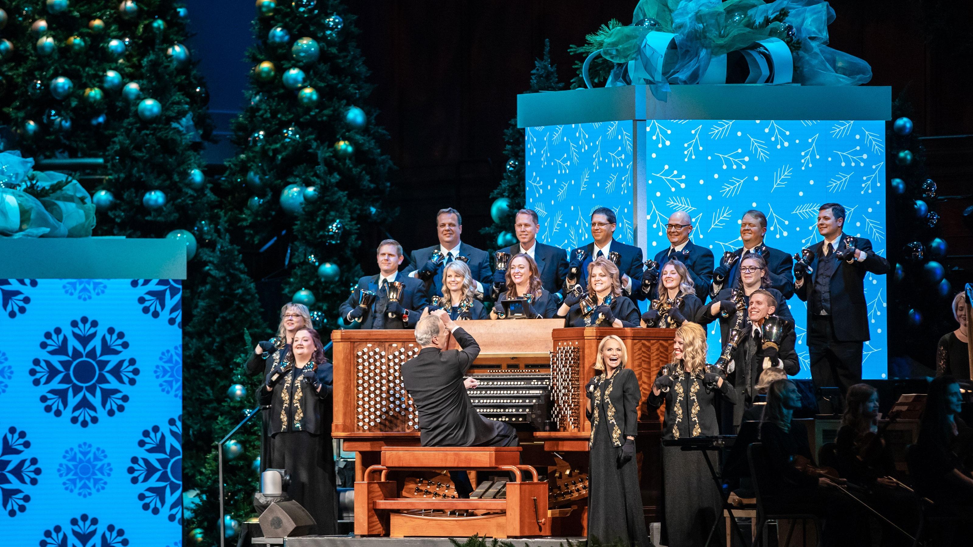 Kristin Chenoweth sings in front of the organist and musicians holding jingle bells.