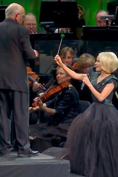 Kristin Chenoweth sings We Need a Little Christmas in front of string musicians and passes Mack Wilberg a percussive mallet.