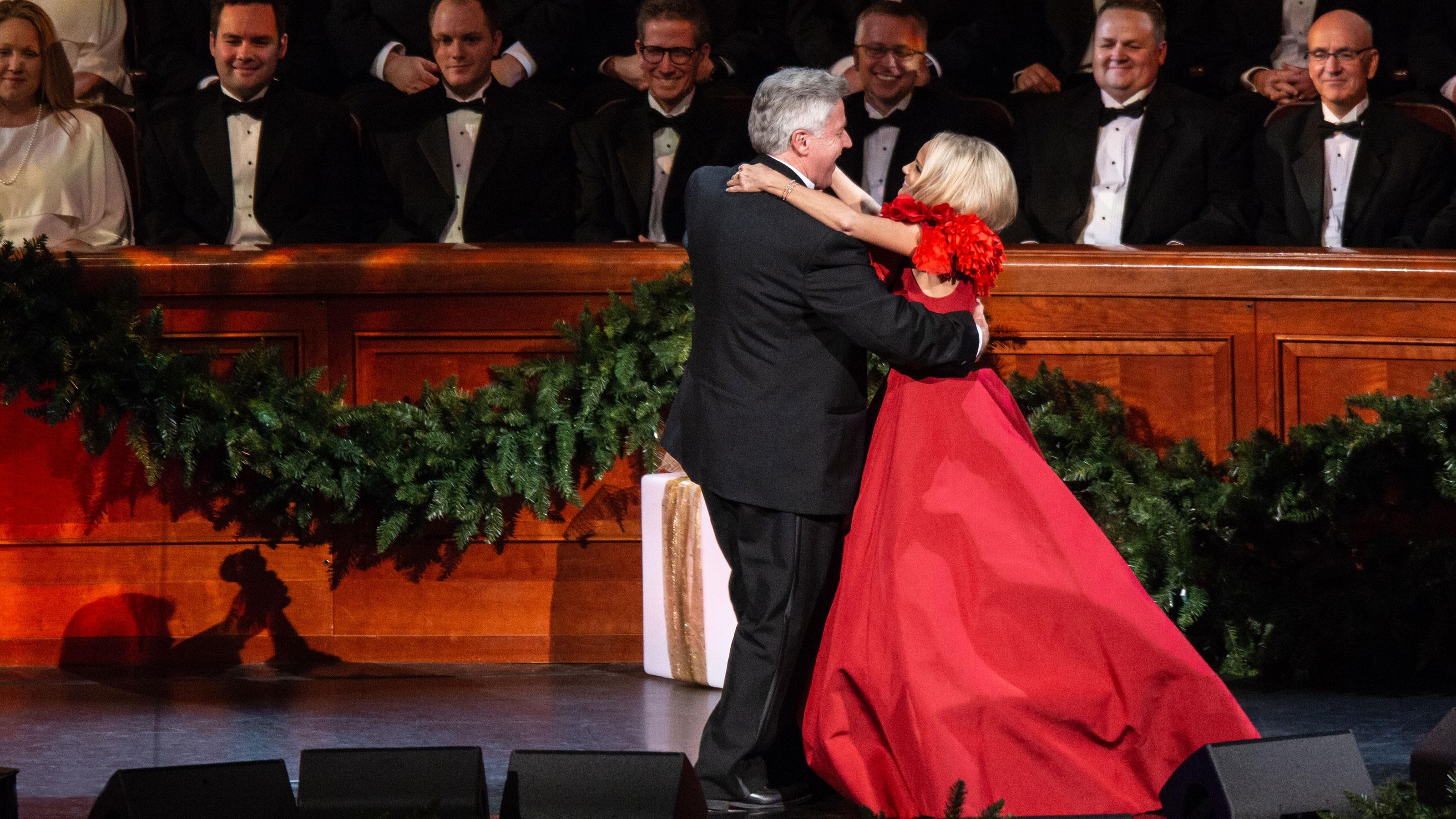 Kristin Chenoweth dances in a red dress with a man in front of The Tabernacle Choir.
