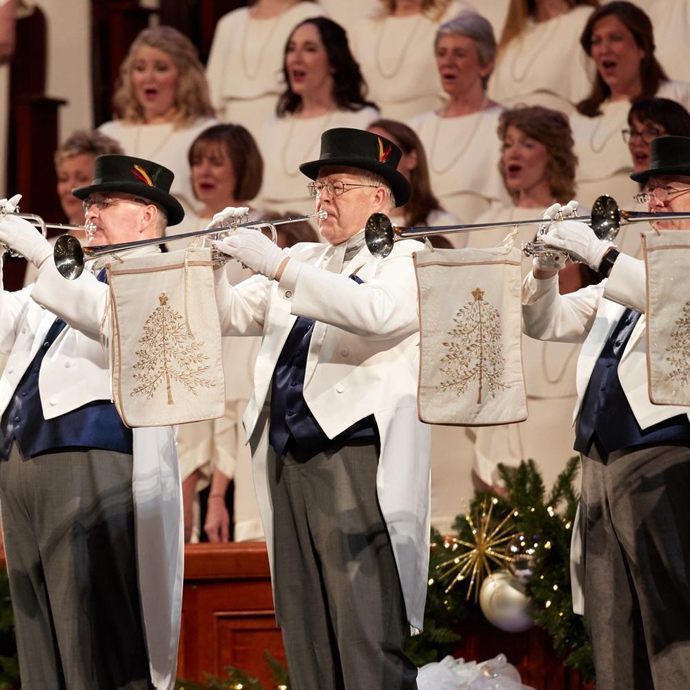 Trumpet players dressed in white coats and top hats play Hark! The Herald Angels Sing.