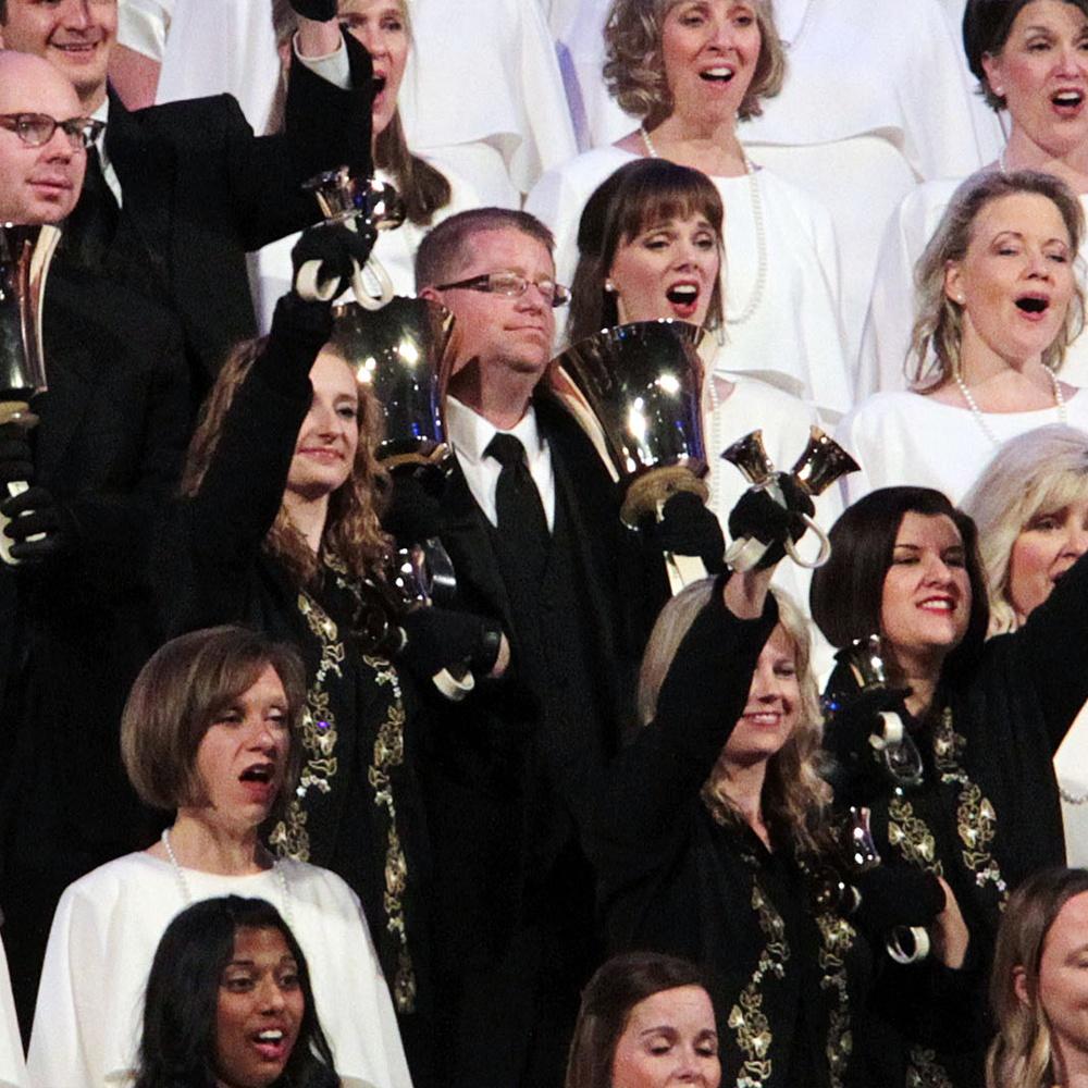 The Tabernacle Choir sings Fill the World with Love while musicians in black suits accompany them on bells.