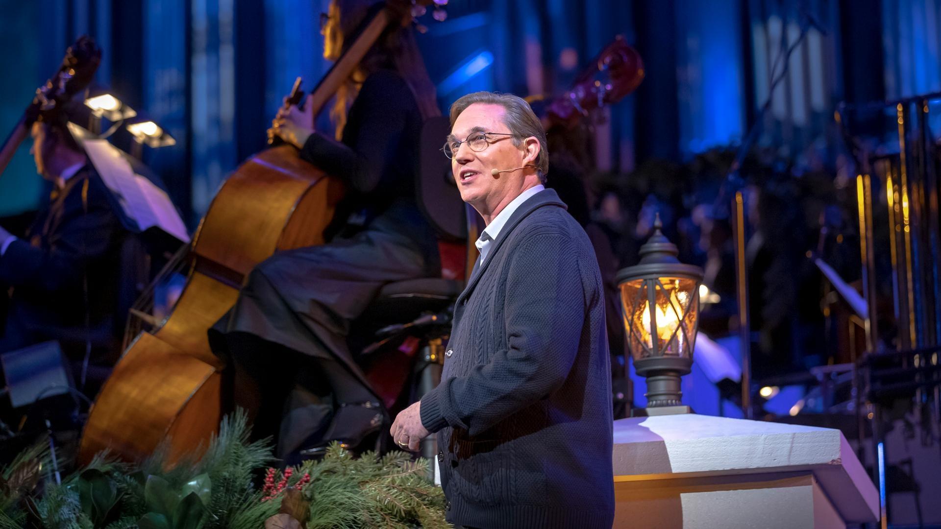 Kristin Chenoweth wears a pale blue dress with fur accents and sings in front of the violinists of The Orchestra at Temple Square.