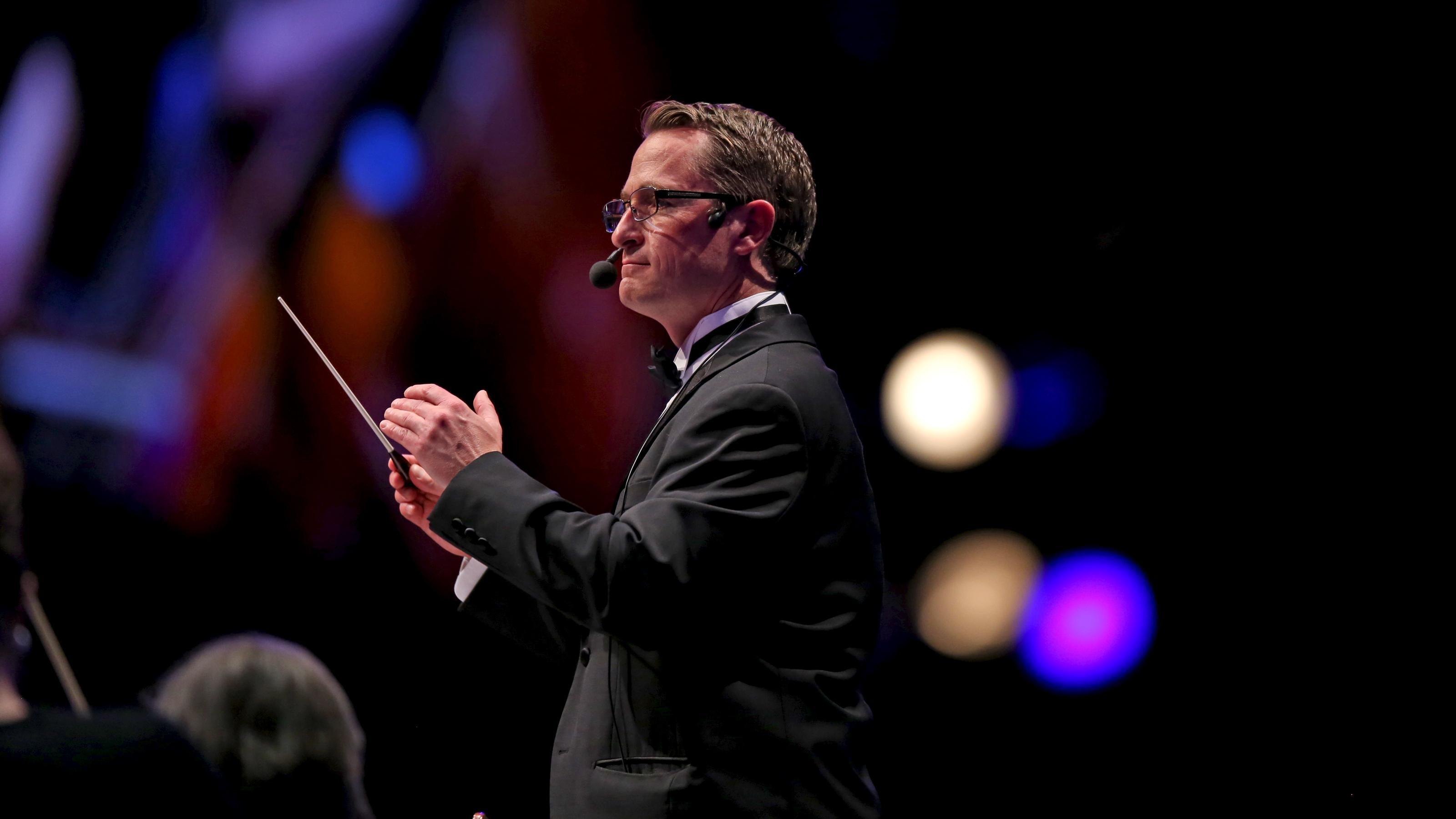 Ryan Murphy, the Associate Music Director of The Tabernacle Choir, wears a headset and conducts musicians.