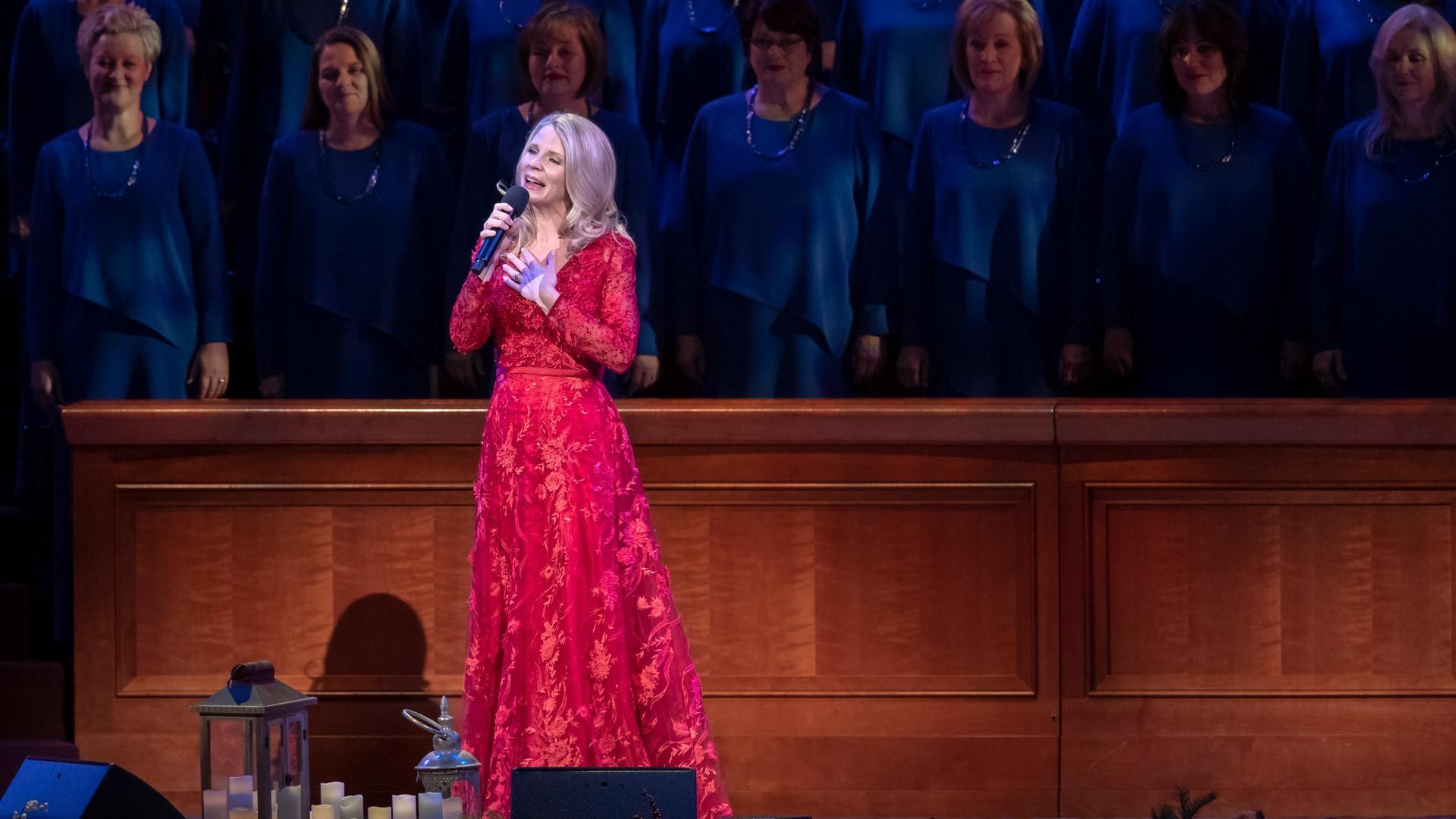 Kristin Chenoweth sings in front of the organist and musicians holding jingle bells.