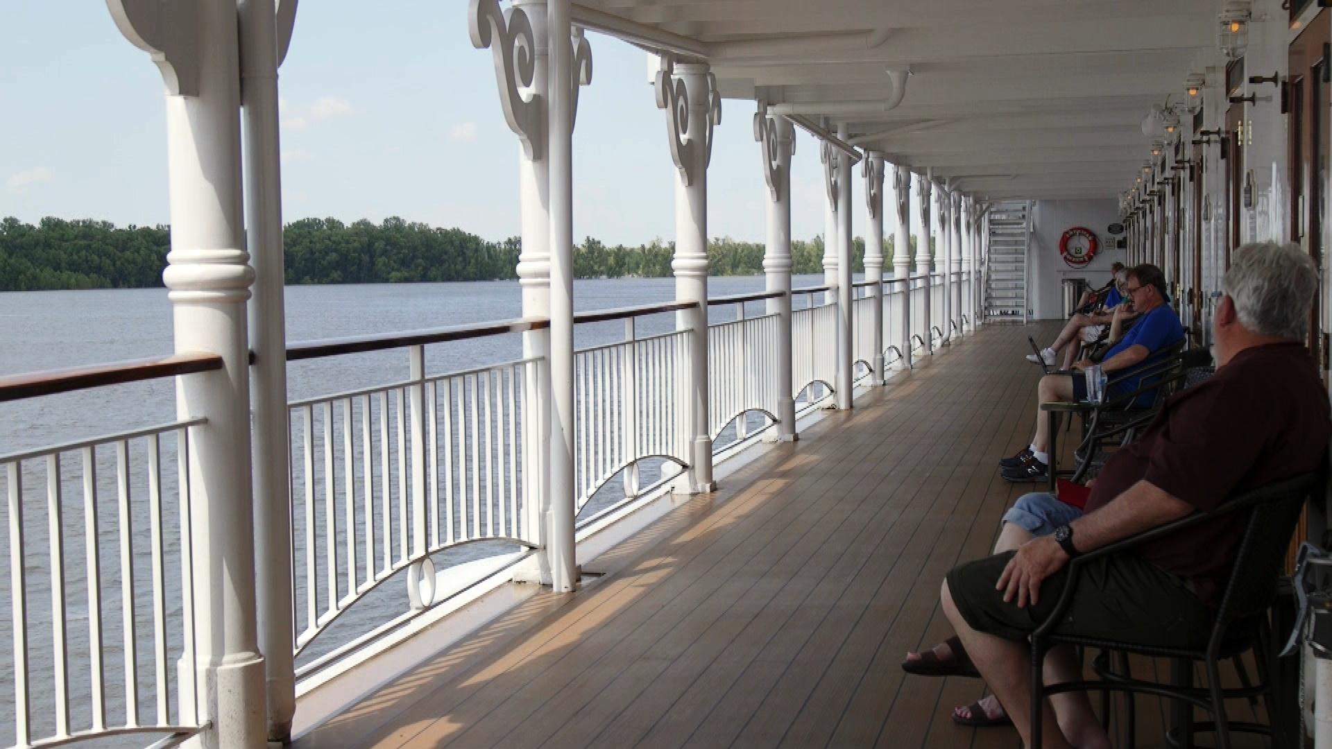 passengers sit along the veranda aboard the American Queen