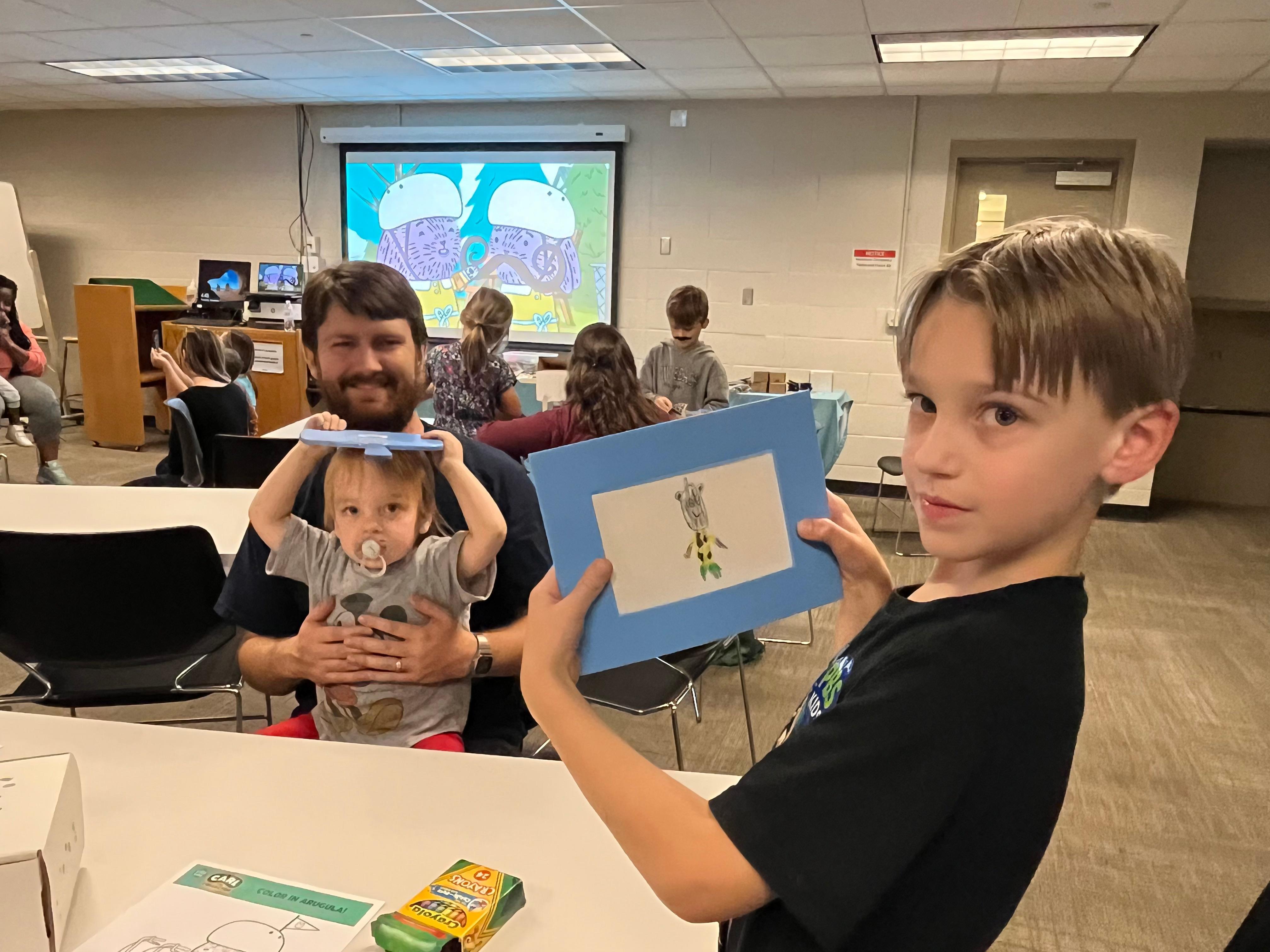 Young children showing off their Carl the Collector drawings while smiling.