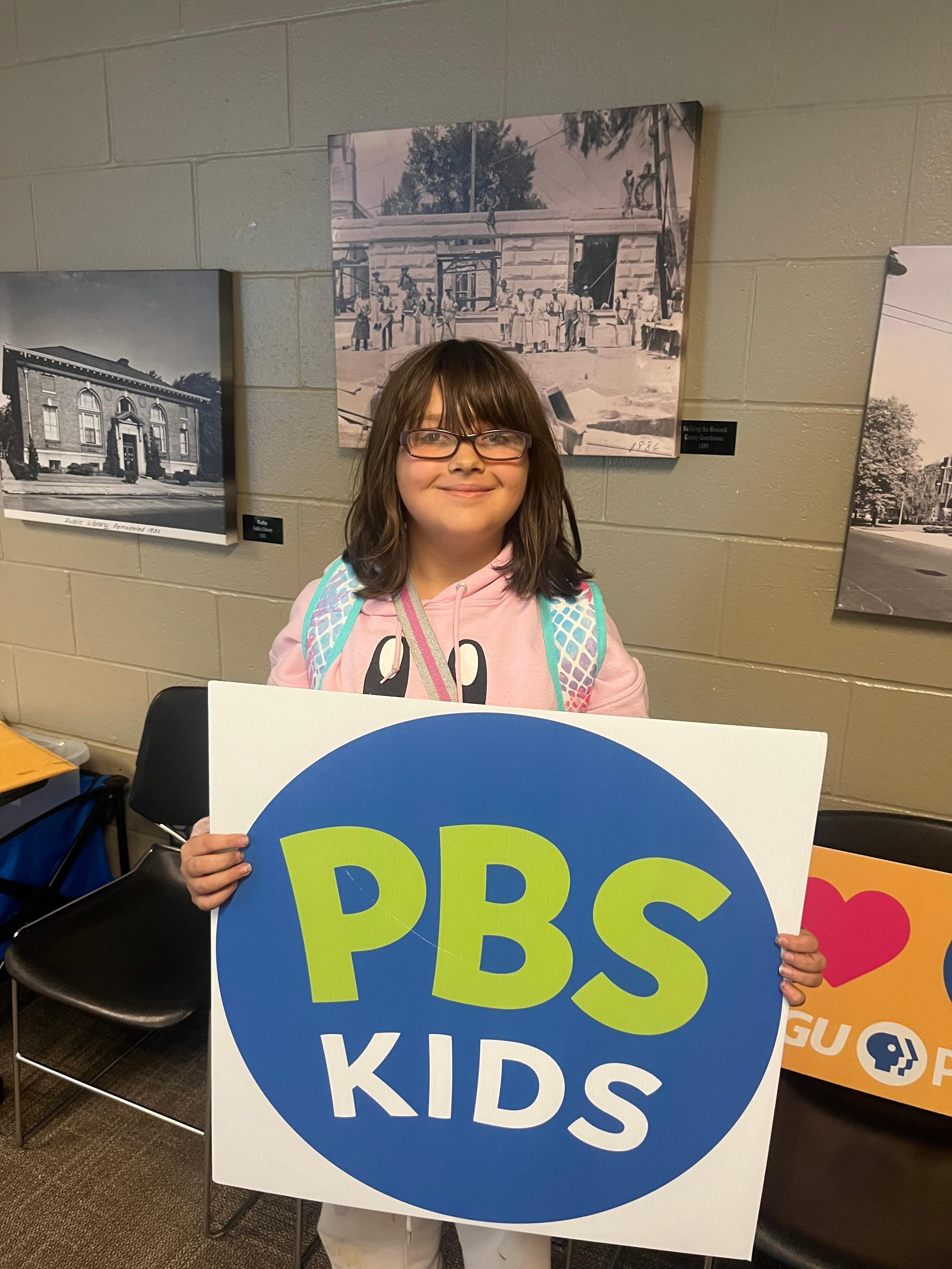 Young girl holding PBS KIDS sign.