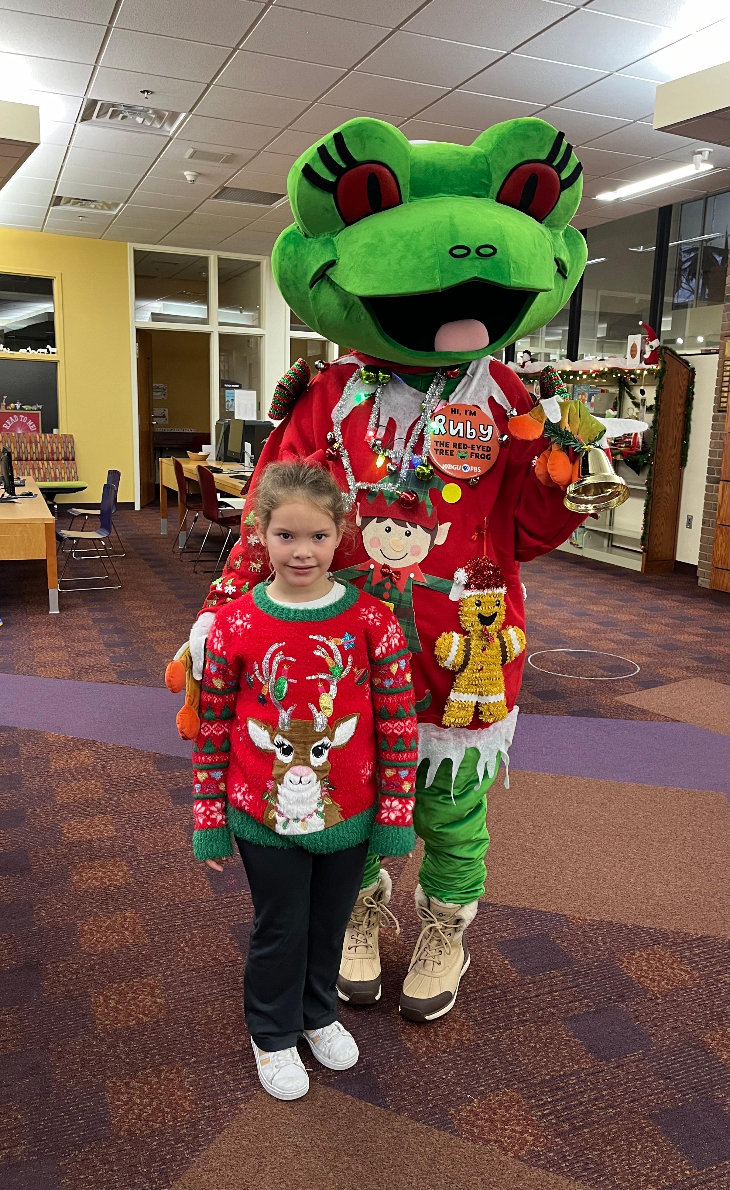 Ruby standing with a girl showing off their christmas sweaters.