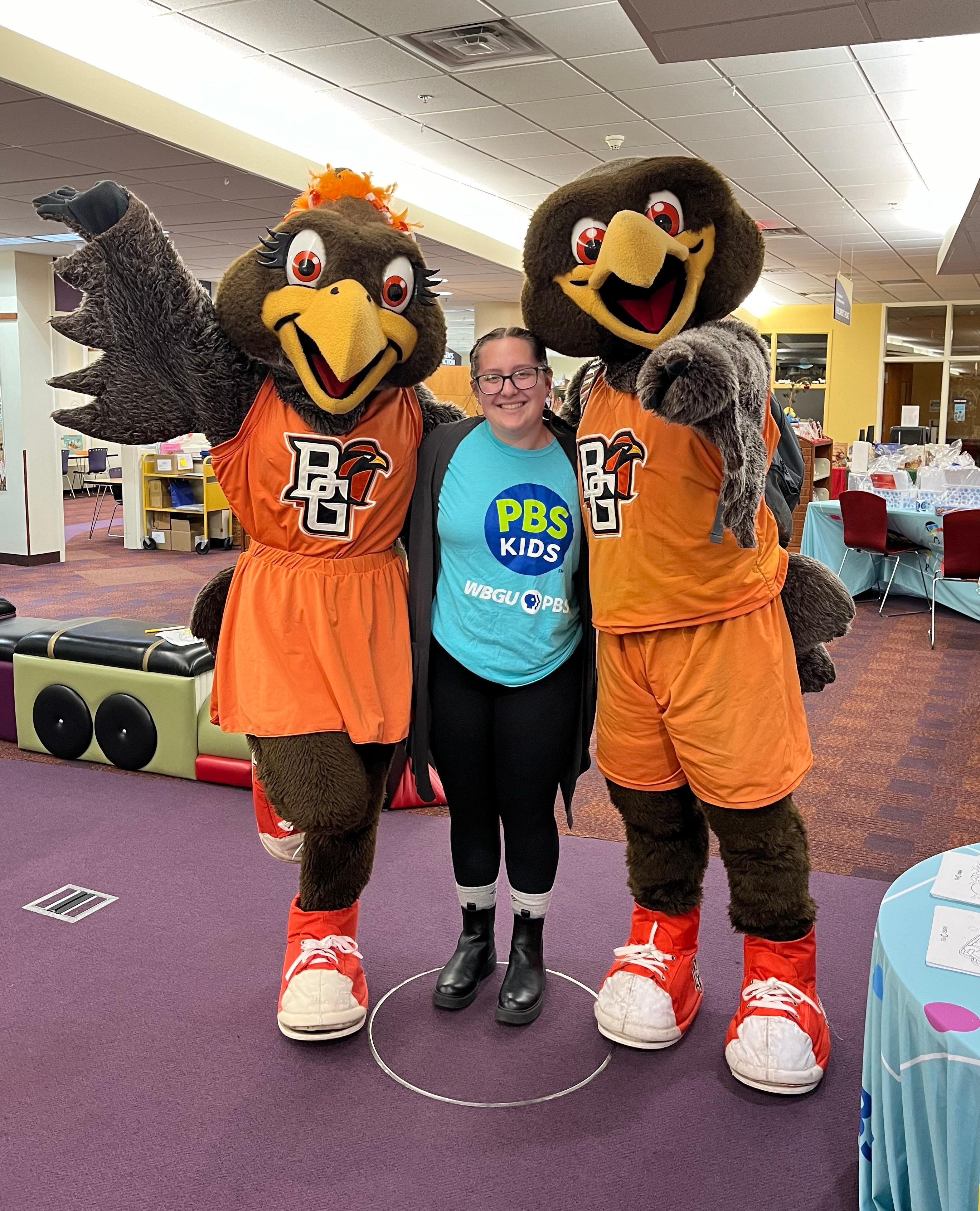 WBGU student employee posing with Freddy and Frieda while wearing PBS KIDS shirt.