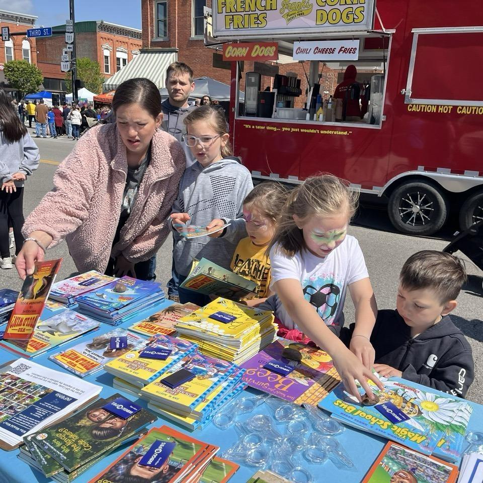 Families browse children's books on a table at the Defiance Lilac Fest on May 9, 2026