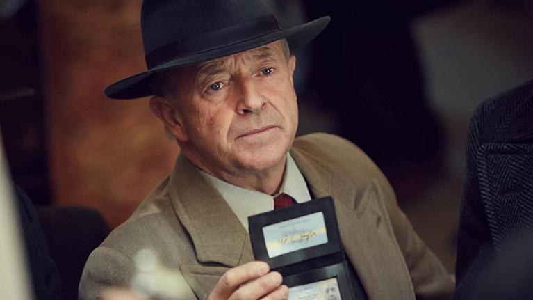 Michael Kitchen as Detective Chief Superintendent Christopher Foyle in Foyle's War, holding a police identification badge.