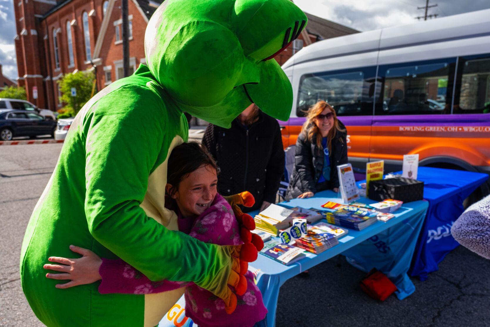 Station mascot Ruby the Red-eyed Tree Frog hugging a girl