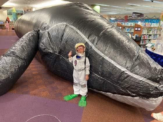Boy dressed as diver standing by inflatable whale