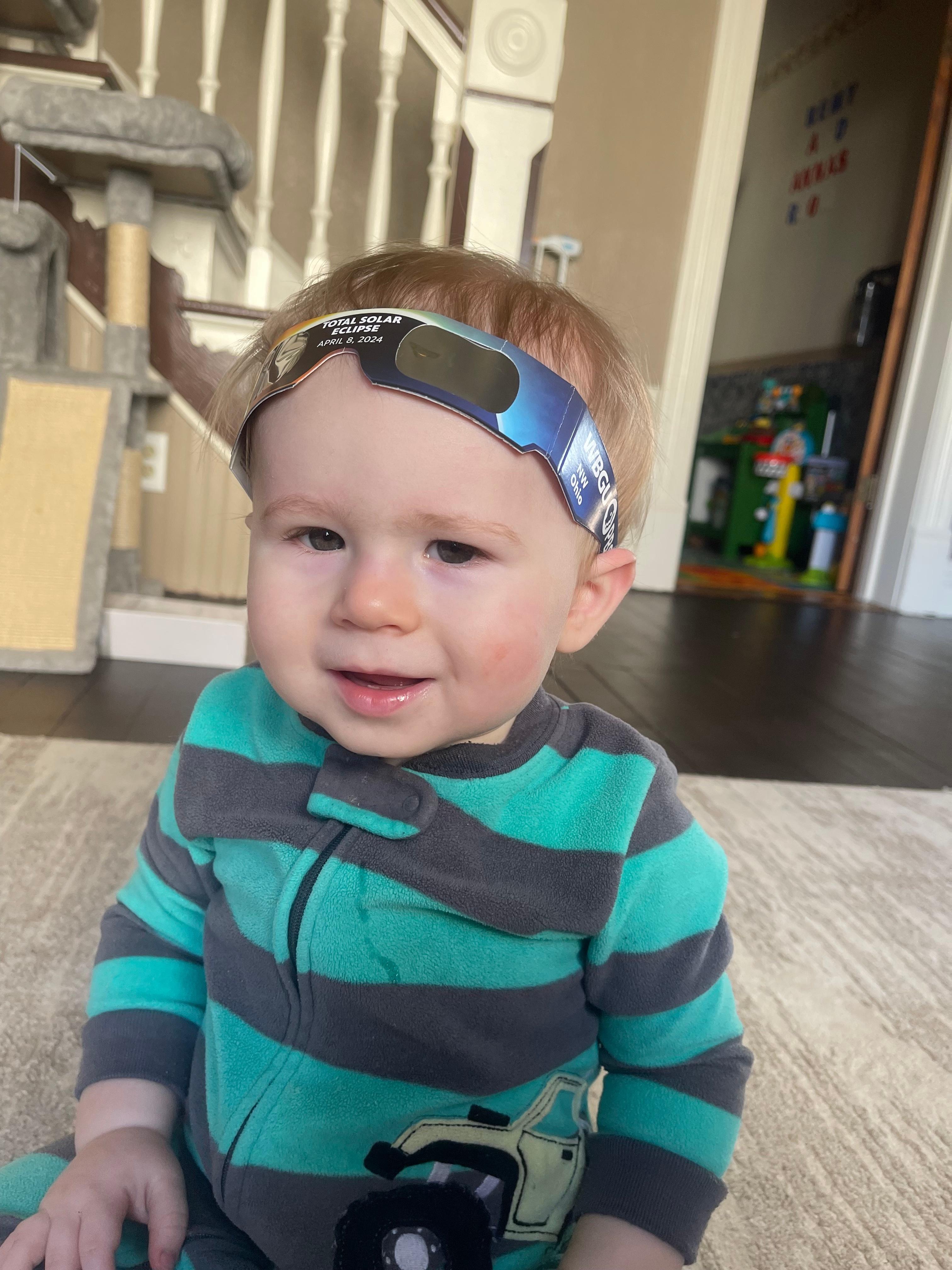Baby with solar eclipse glasses propped on forehead
