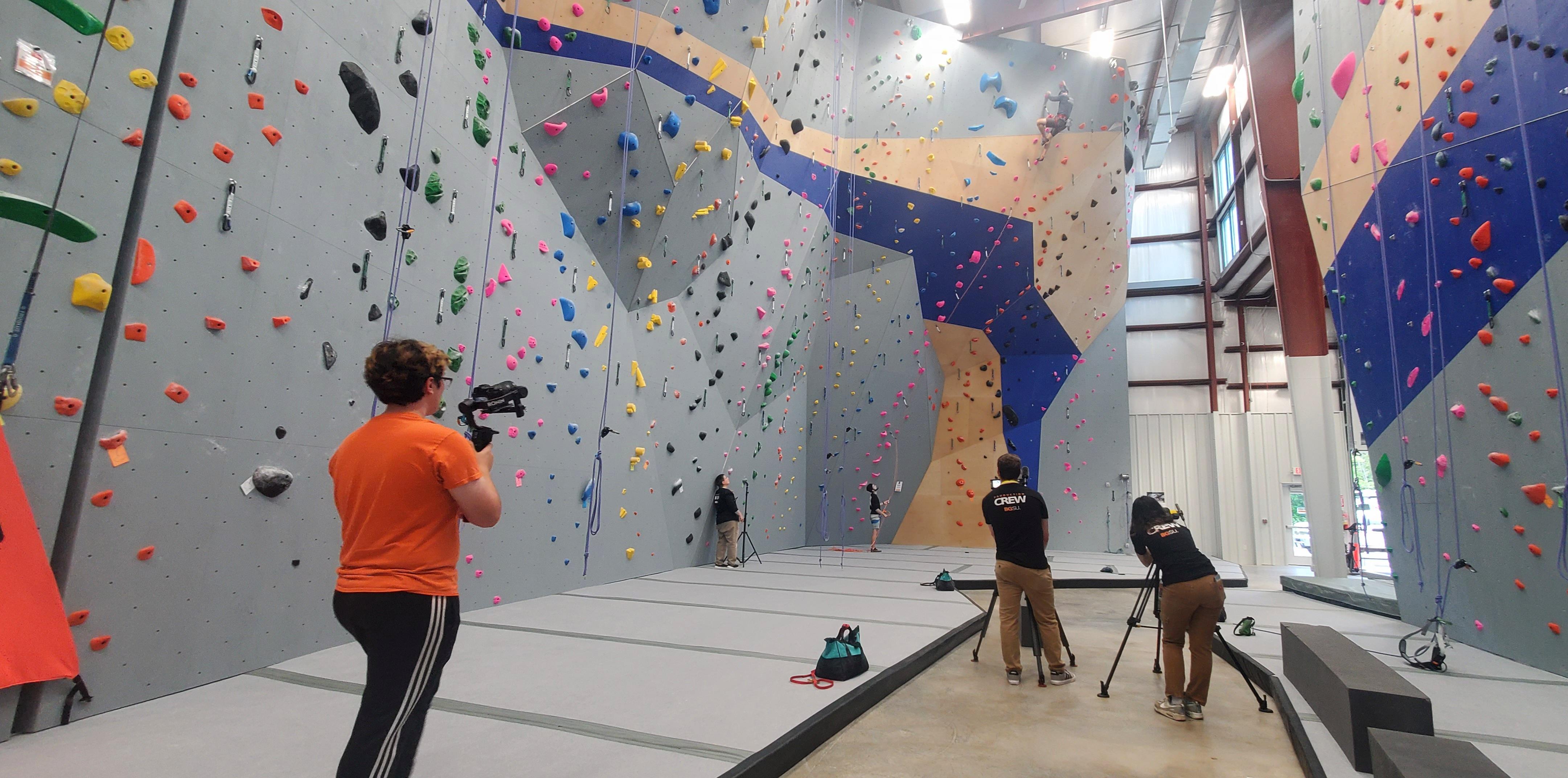 Videographers filming indoor rock climbing