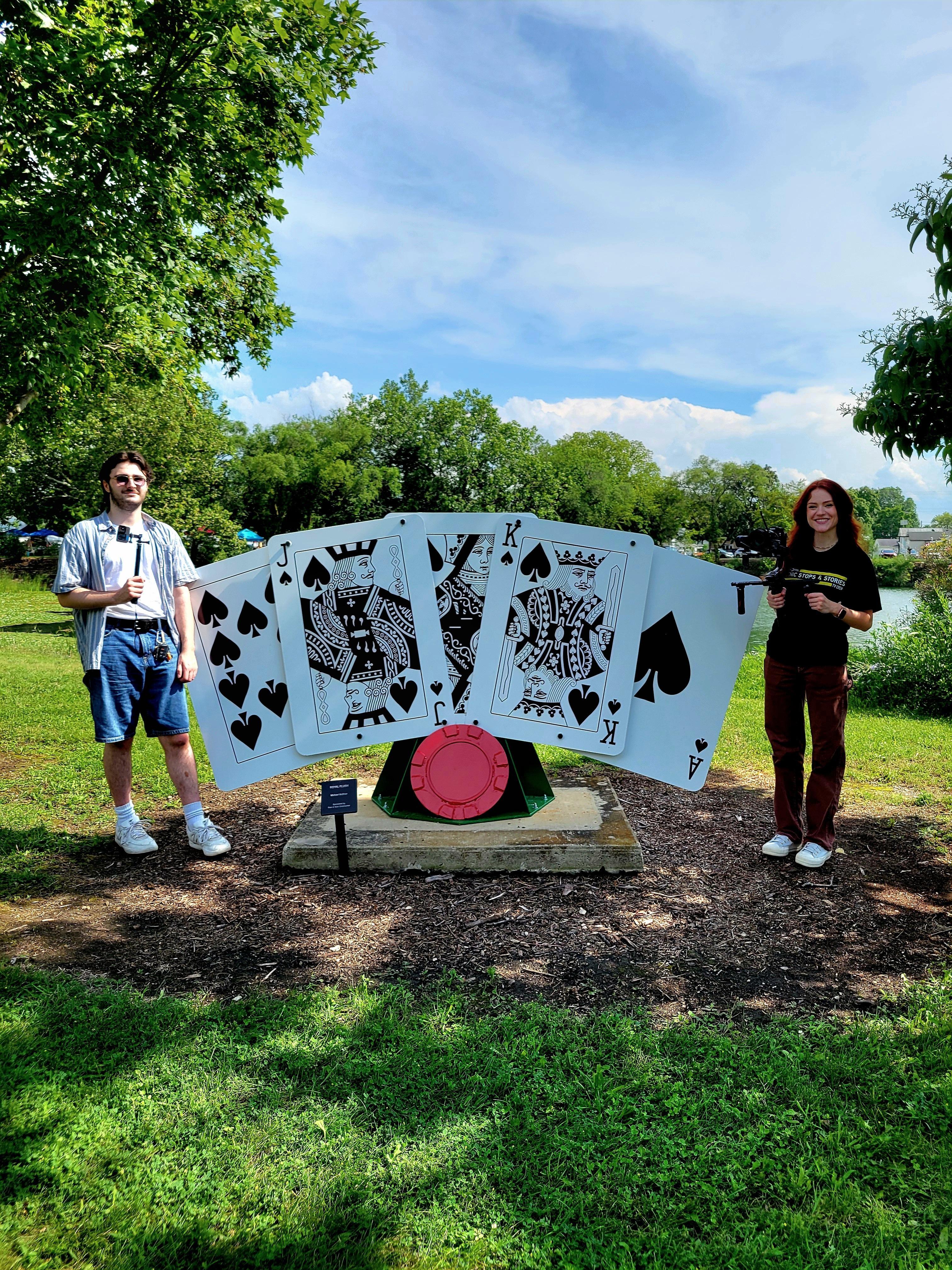 2 students standing by giant playing cards