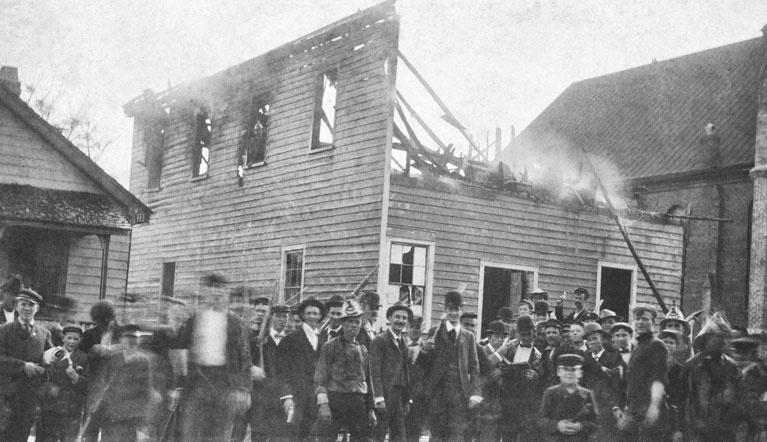 Soldiers in 1898 standing in front of a burning building