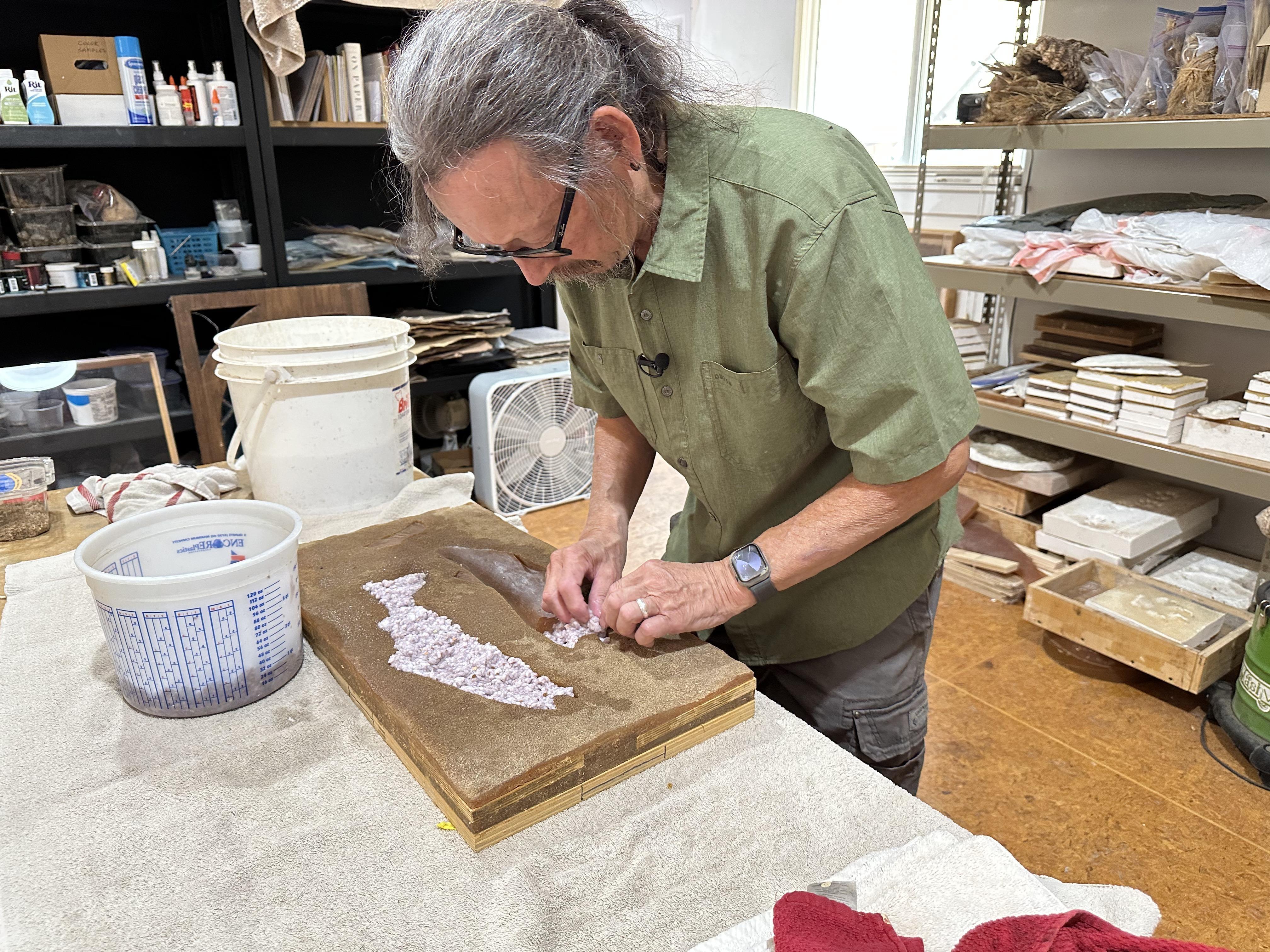 Artist Lonnie Hutson making paper-cast fish