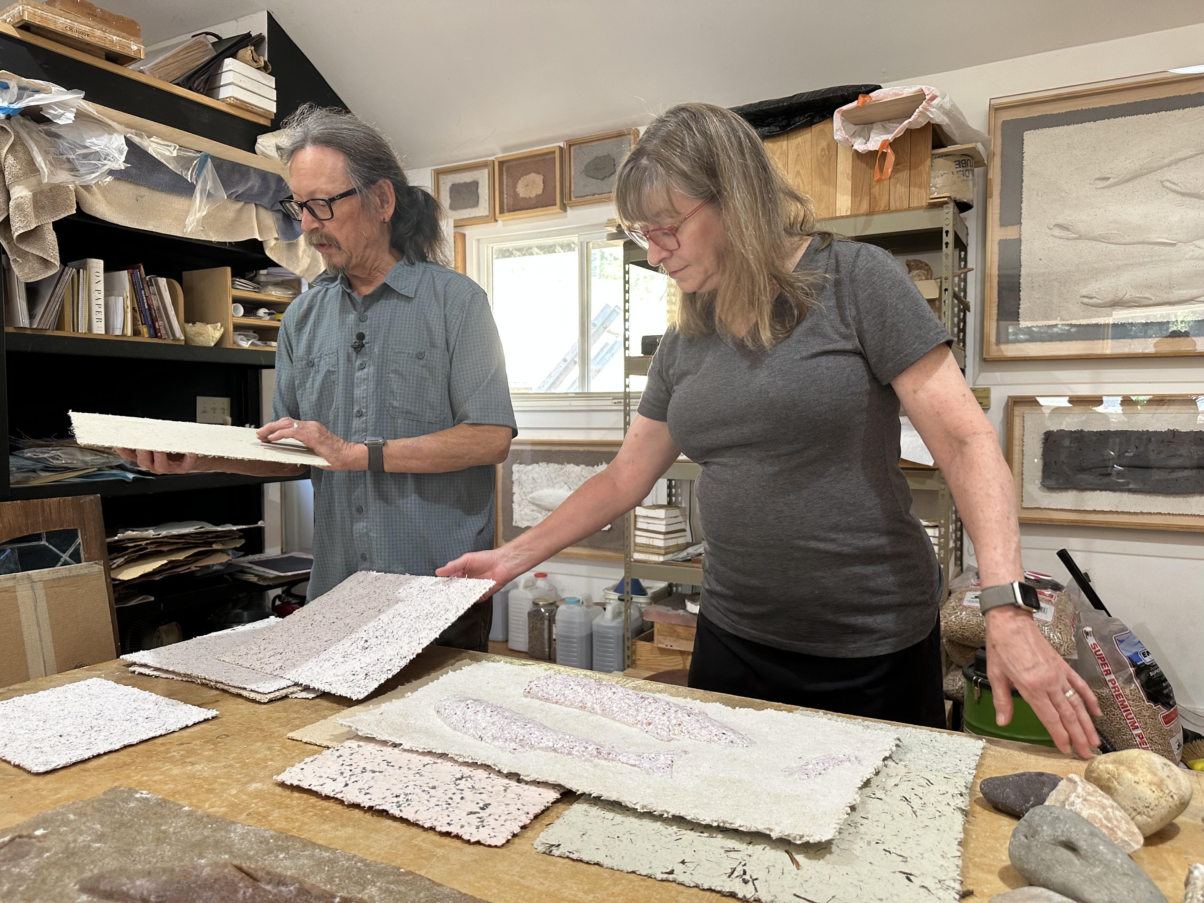 Artist Gail Siegel helping husband Lonnie Hutson choose a background for his paper-cast fish