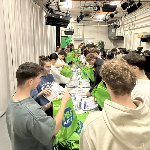 Volunteers pack green bags full of kindergarten kits
