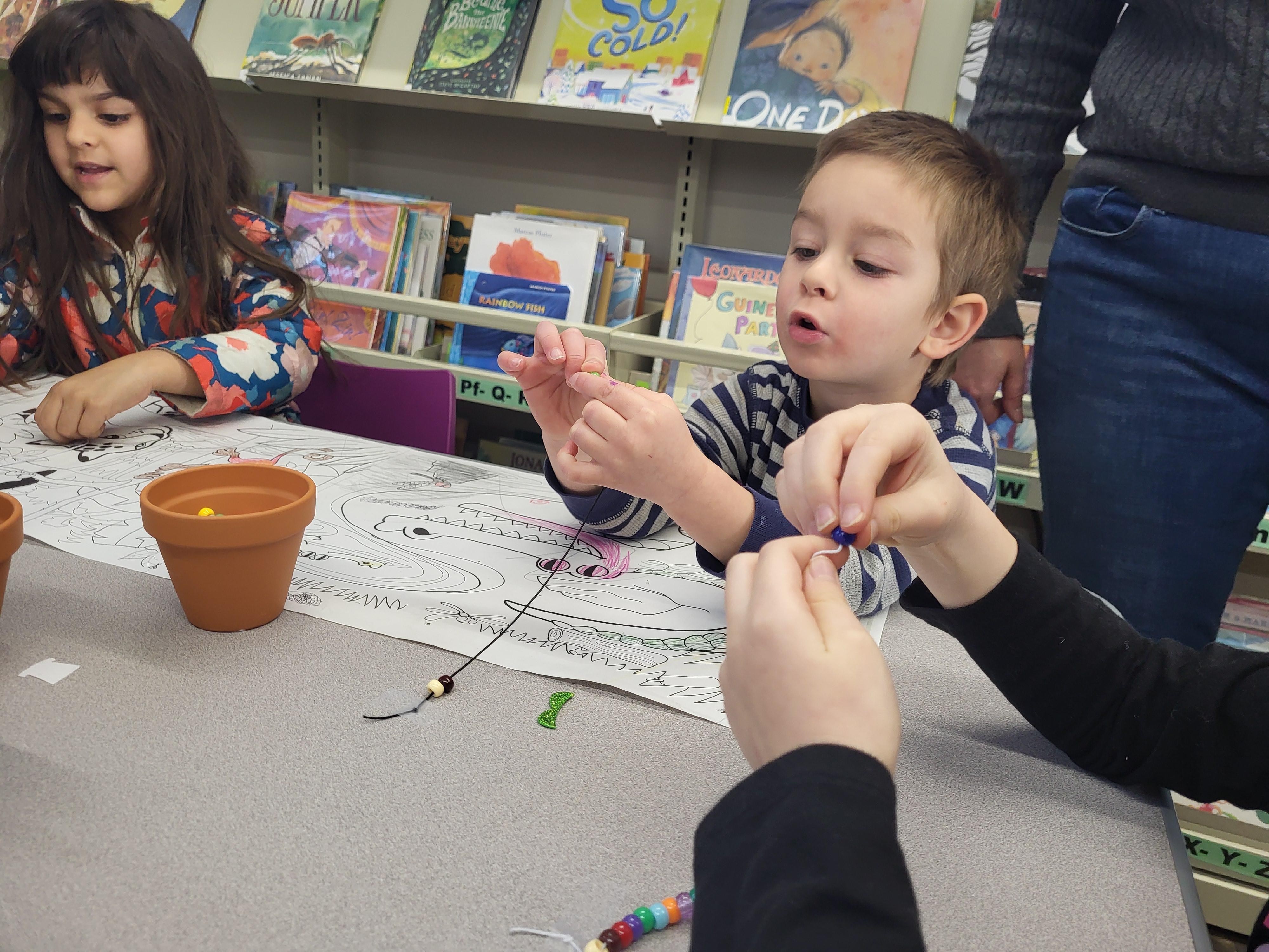 A small boy crafts with beads