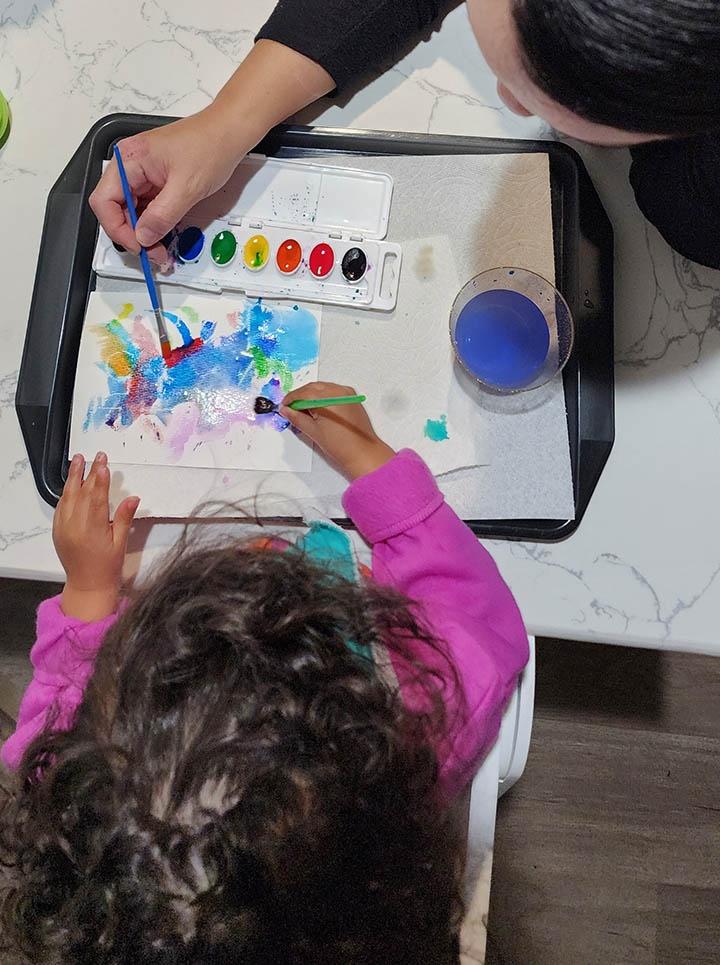 Aerial view of a kid painting with watercolors
