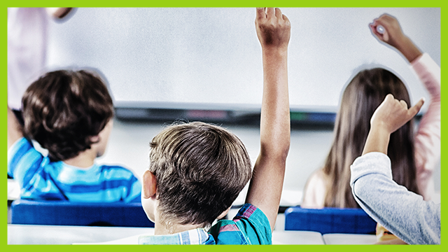 Children raising their hands in class