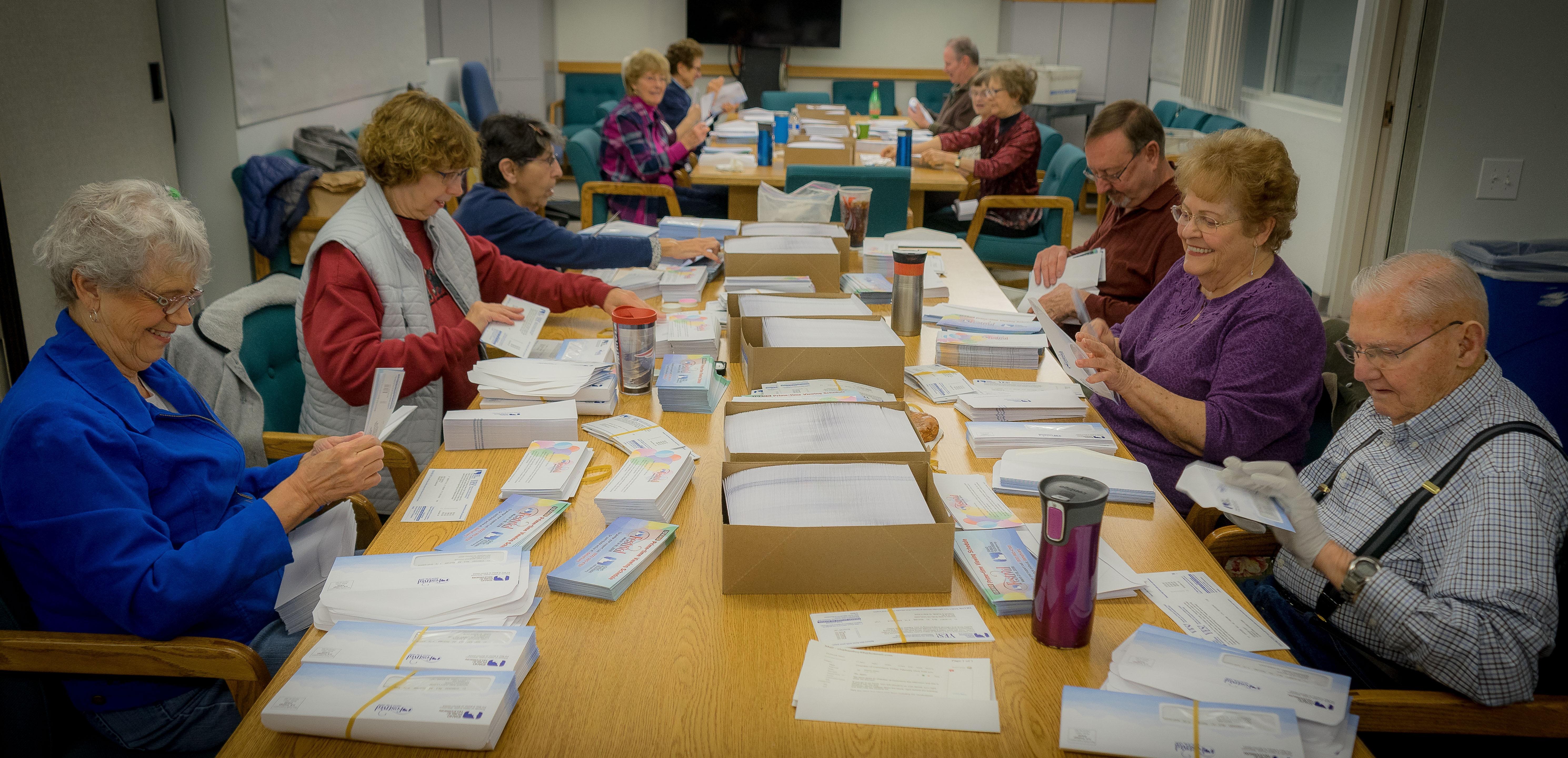 Volunteers stuffing envelopes with mailers