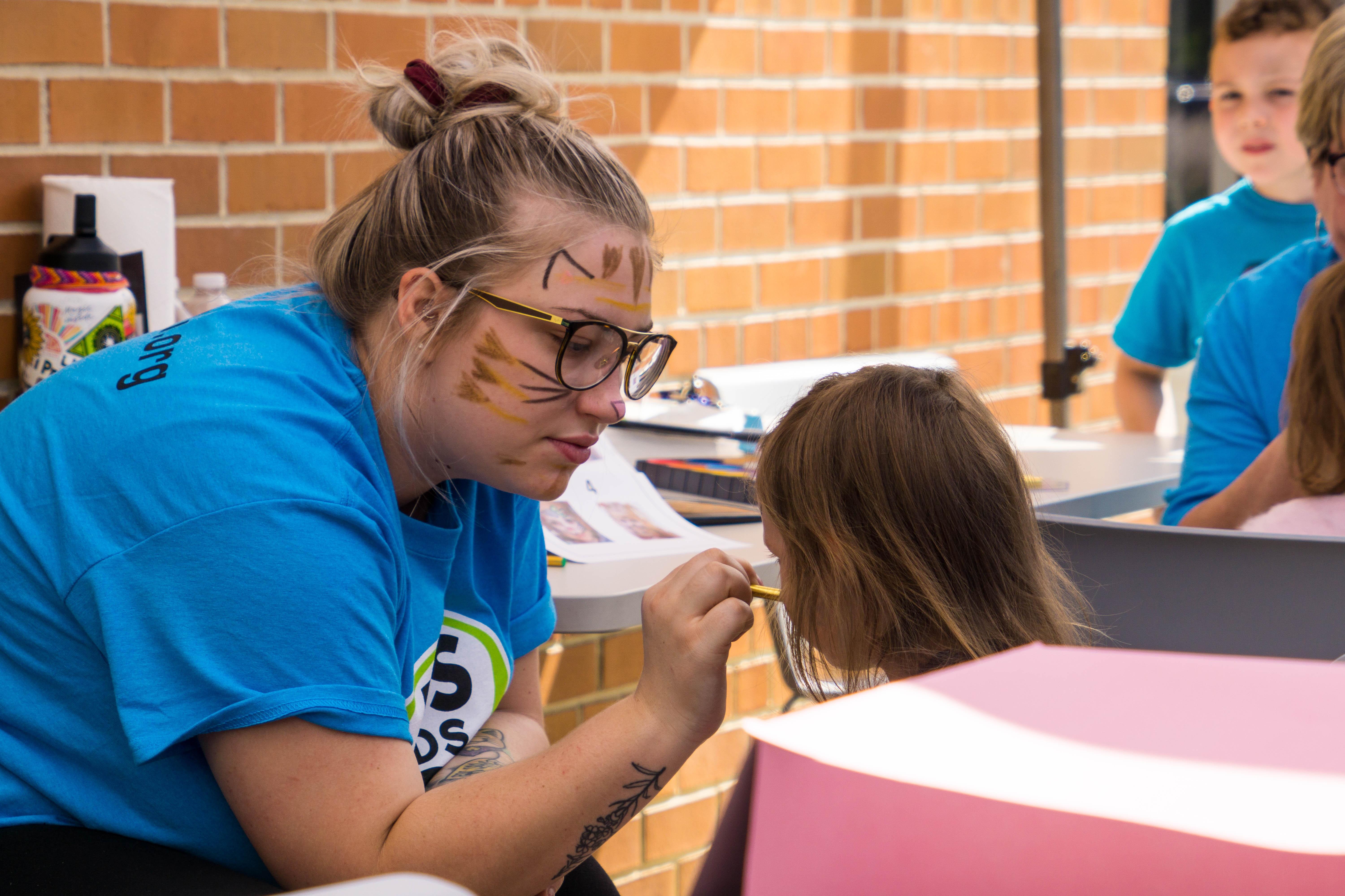 Volunteer face painting at kids event