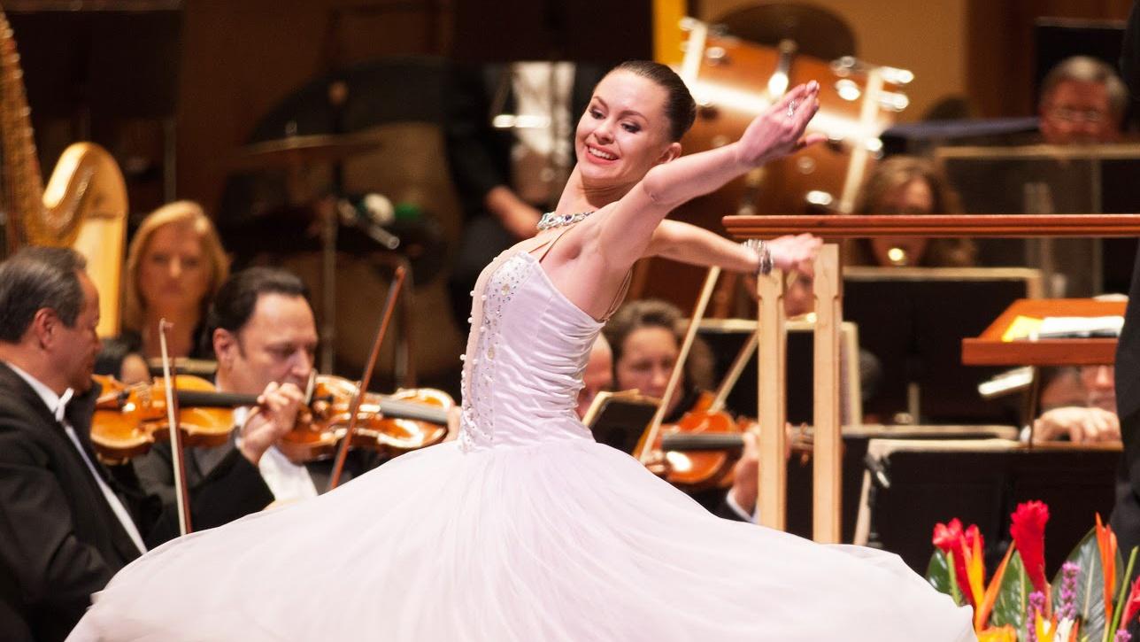 Photo of a ballerina dancing as an orchestra plays in the background