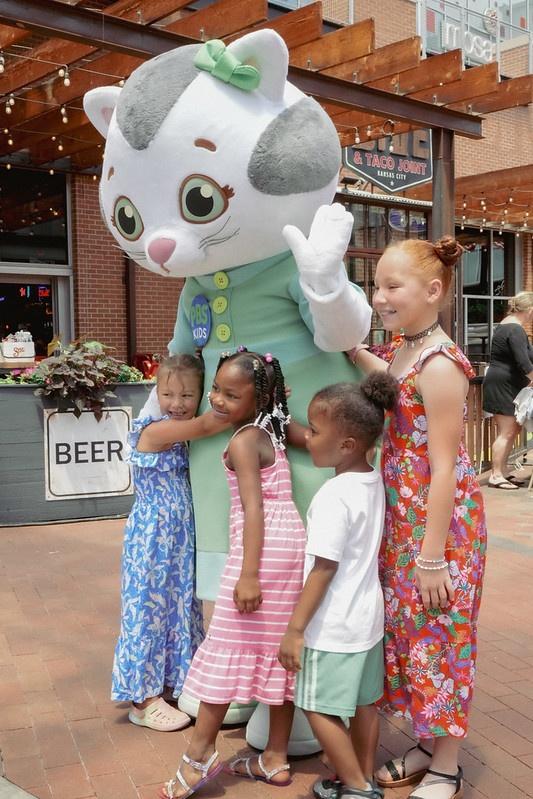 Four kids pose for a photo with a character from Daniel Tiger's Neighborhood.