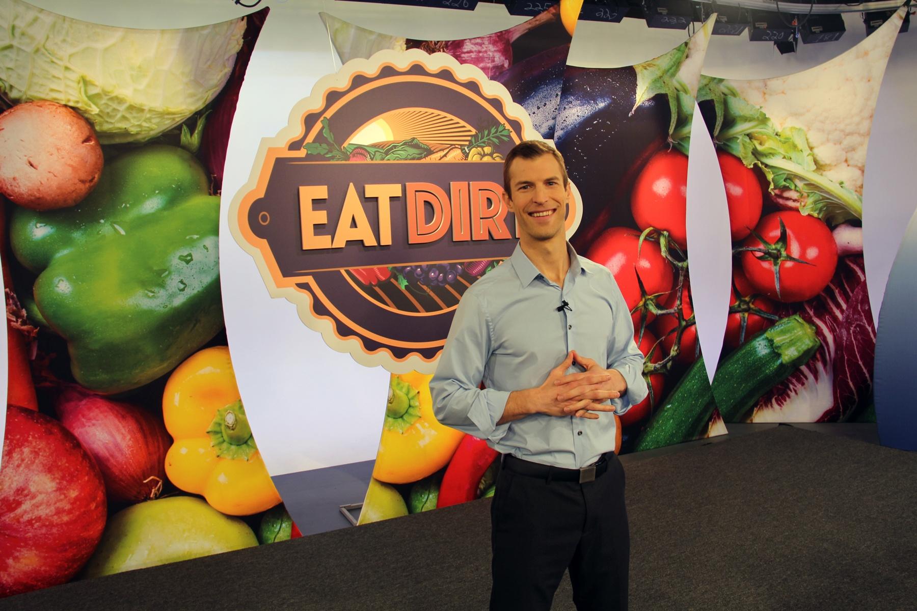 Man stands in front of sign that says "Eat Dirt"