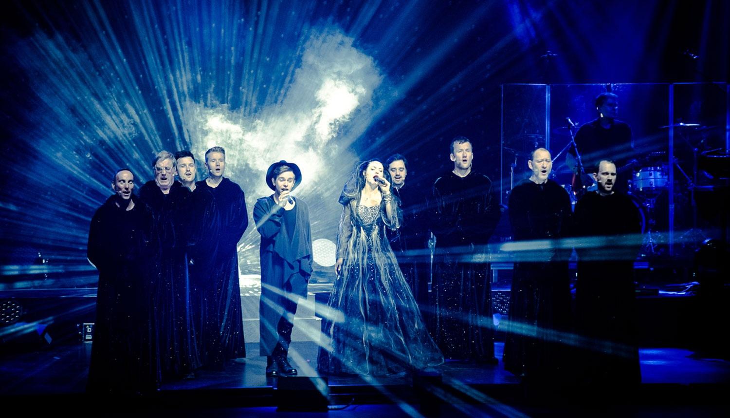 Performers on stage with blue lights, smoke