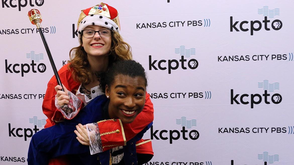 One girl piggybacks on another, both dressed in Hamilton clothes and props