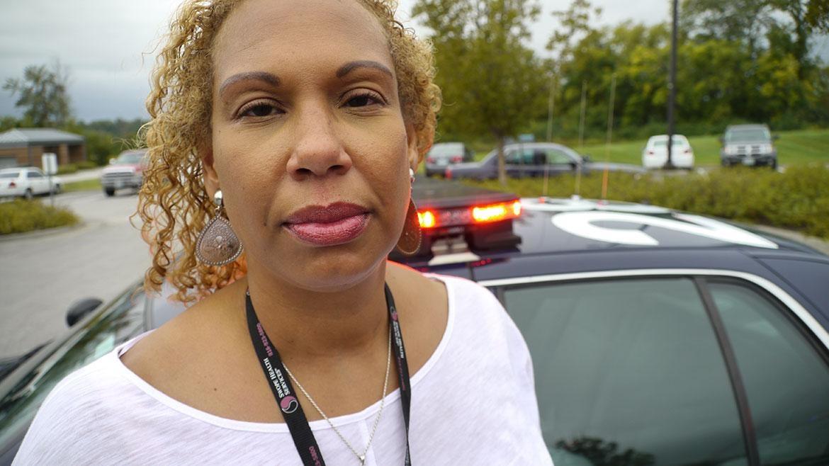 Photo of a woman standing in front of a police car