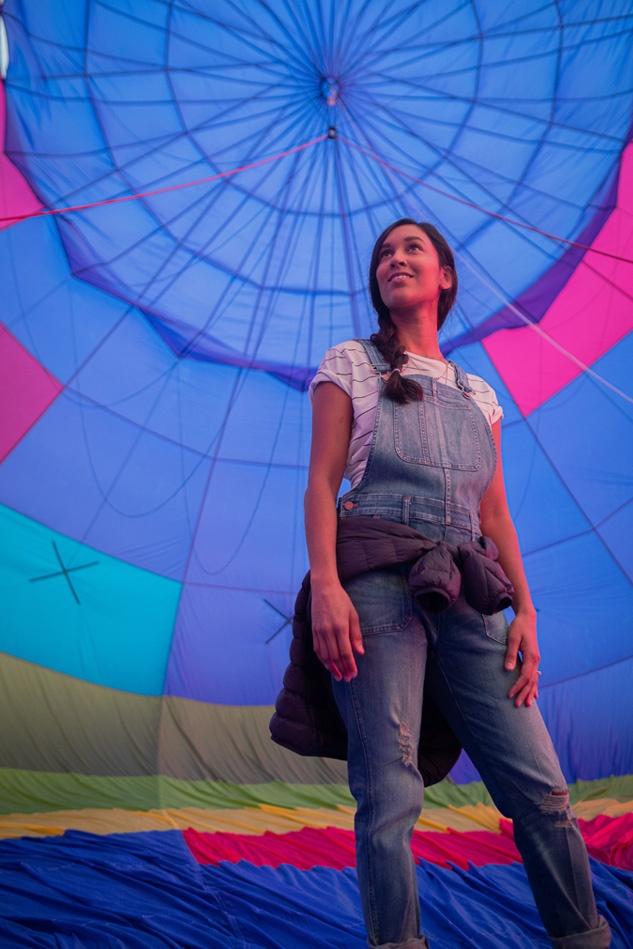Woman in overalls smiling inside partially inflated hot air balloon
