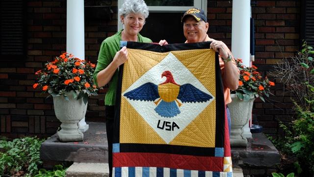 USA quilt held by woman and veteran