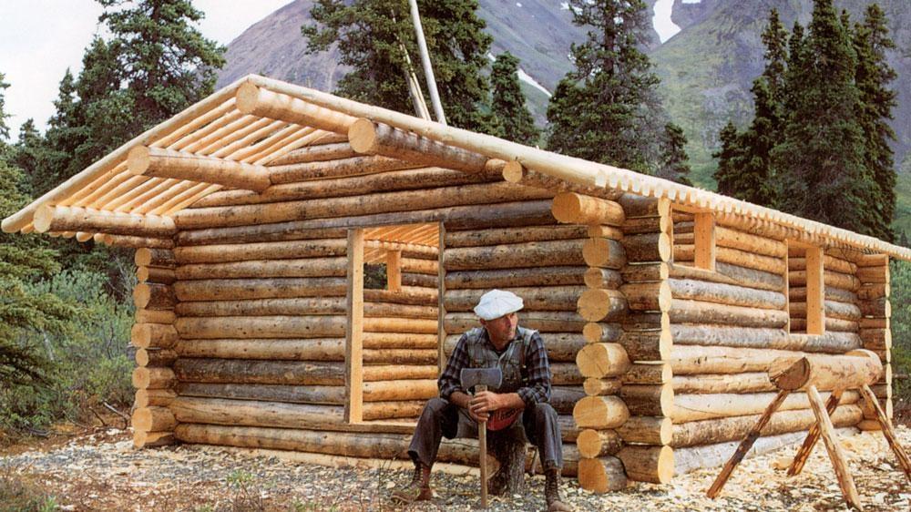 Dick Proenneke sits in front of his cabin