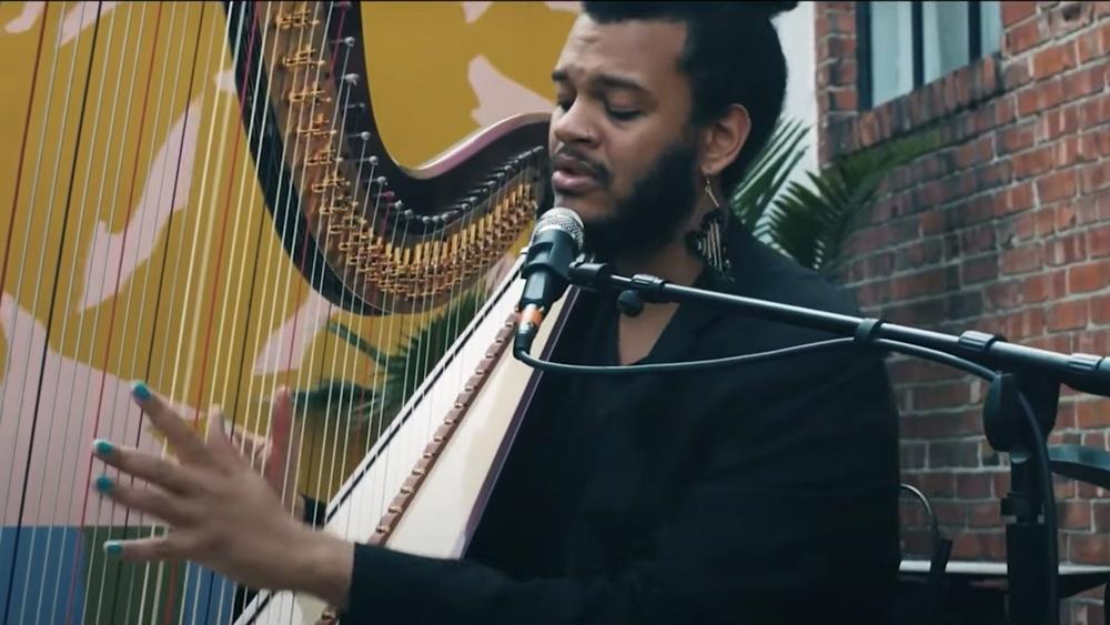 Calvin Arsenia plays harp and sings into microphone