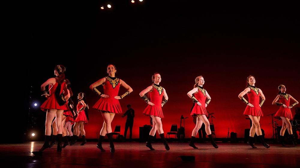 Group of women Irish dancing wearing red dresses