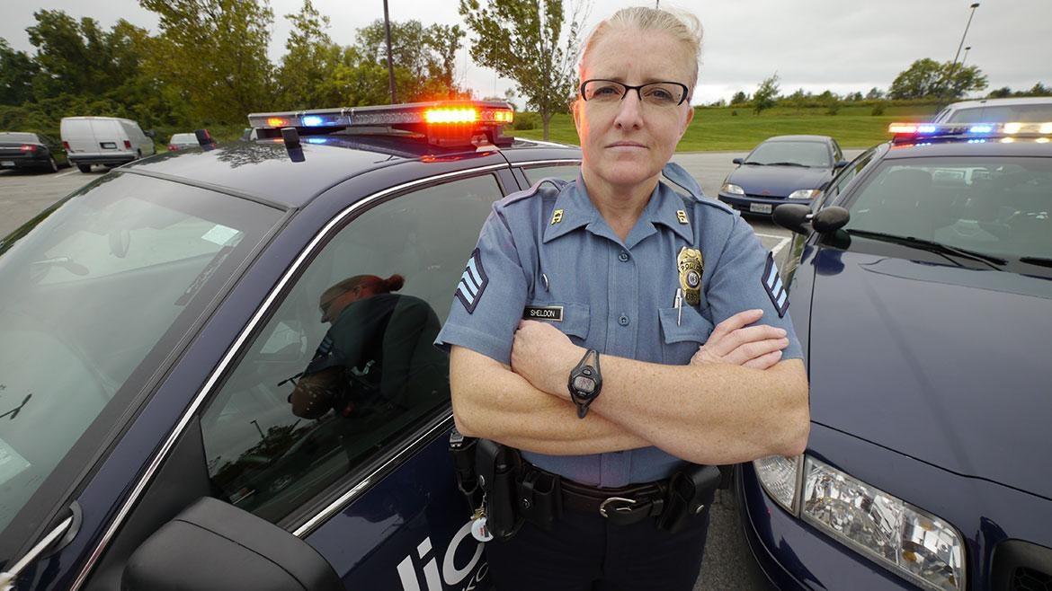 Photo of a female police officer in uniform in front of police cars