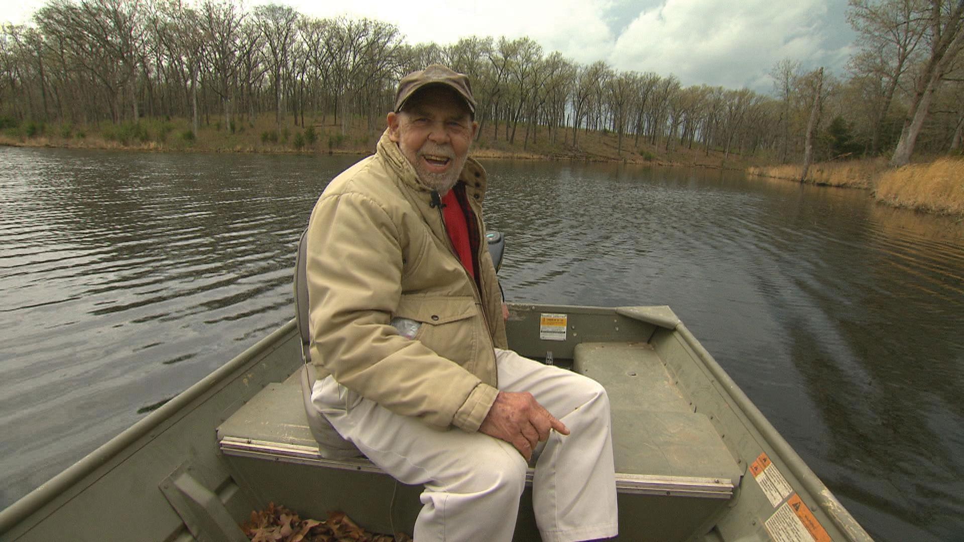 Many sits in a boat on the lake smiling