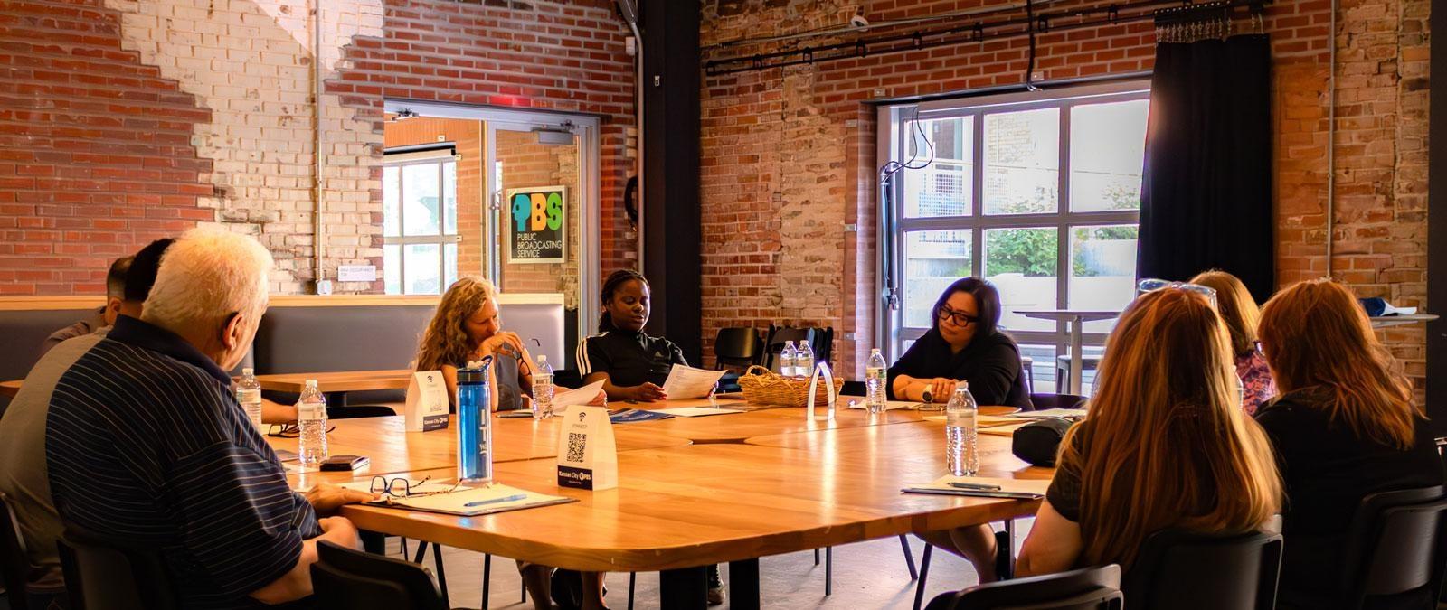 People sitting around table in brick walled room.